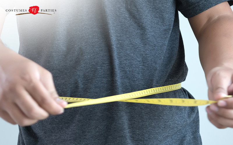 A man measuring his waist size with a measuring tape